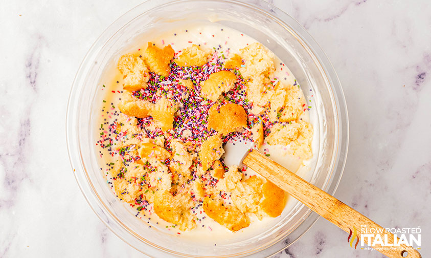 adding cupcake crumbles and sprinkles to ice cream mixture