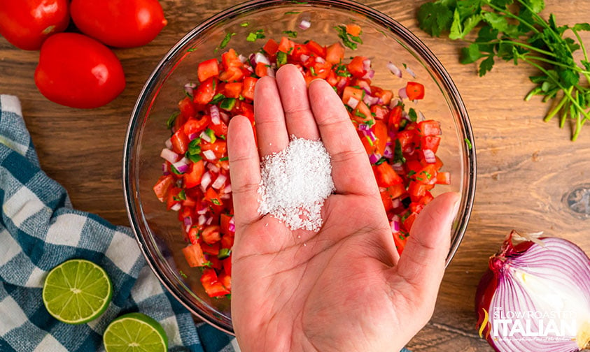 adding salt to a bowl of chipotle mexican grill fresh tomato salsa