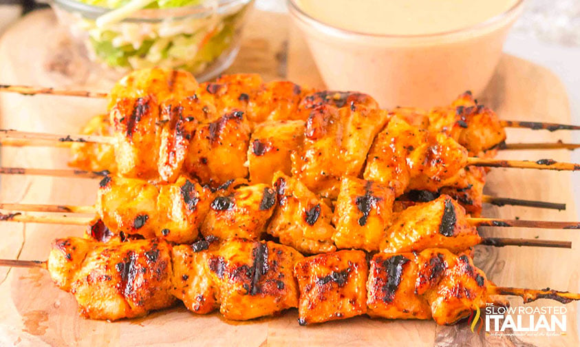 bang bang chicken skewers lined on a plate with dipping sauce