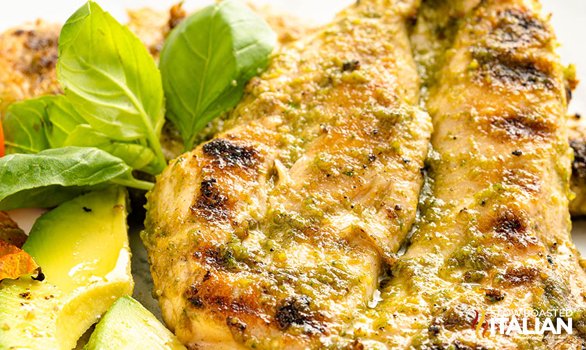 grilled pesto chicken on a plate with avocado and basil