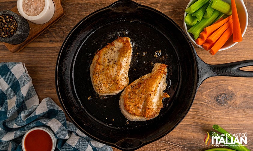 golden brown seasoned chicken breasts in a cast iron skillet