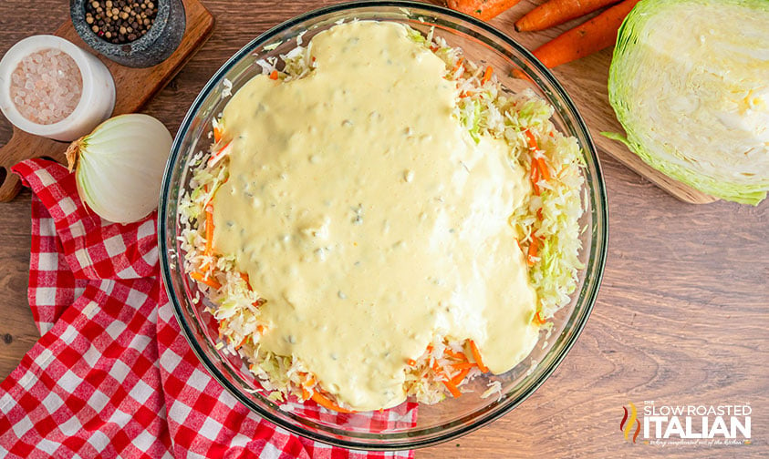 adding dressing to bowl of coleslaw ingredients