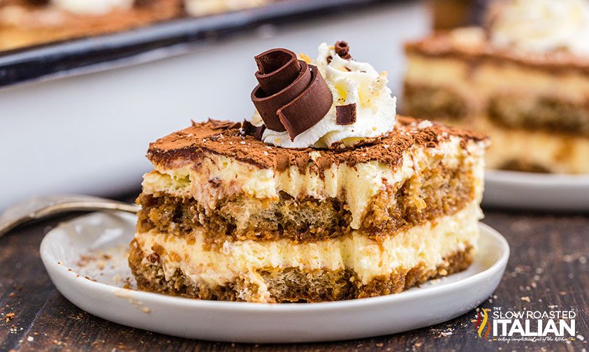 slice of tiramisu topped with whipped cream and chocolate curl