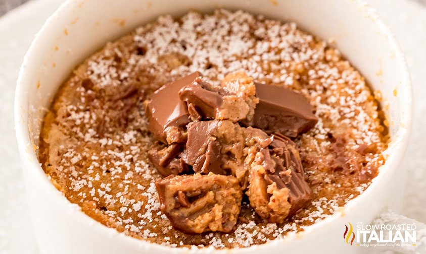 Nutter Butter mug cake topped with chopped Reeses and powdered sugar