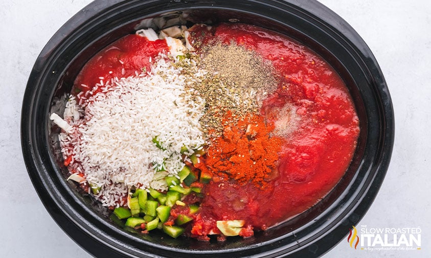 adding seasoning, tomatoes, peppers, rice and cabbage to crockpot