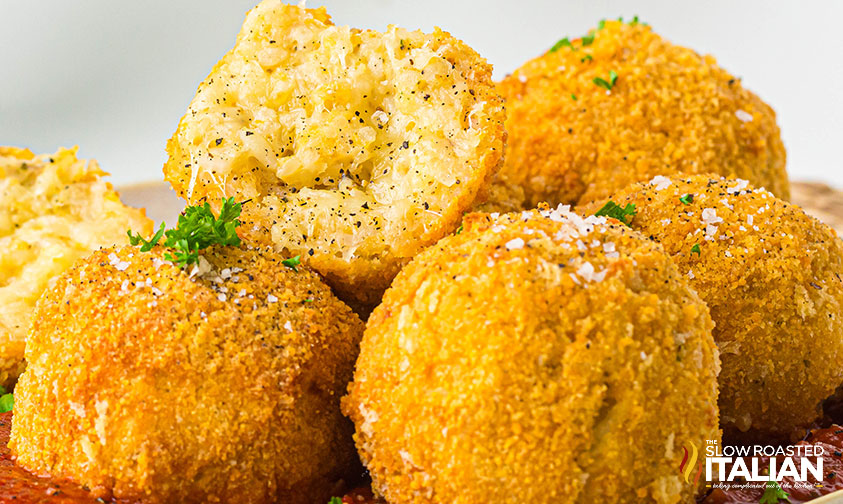 closeup or arancini balls on a plate with marinara sauce