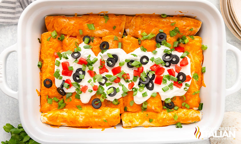 baked beef enchiladas in a baking dish with toppings