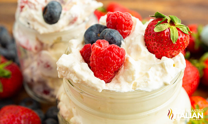 closeup of keto cheesecake fluff in a jar topped with fresh berries