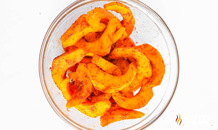 seasoning on pumpkin fries in a mixing bowl