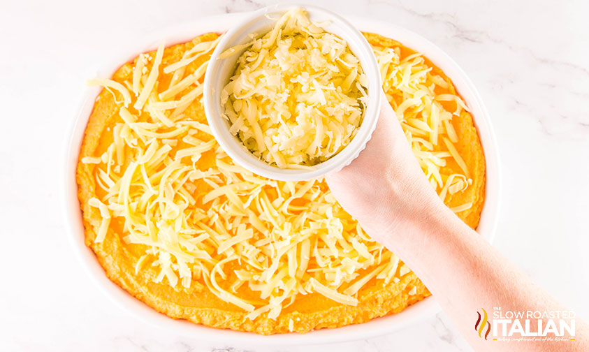 sweet potato mixture added to casserole dish with shredded cheese on top