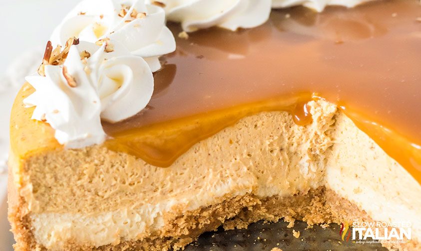 showing the inside of a New York style pumpkin cheesecake topped with caramel and a whipped cream border