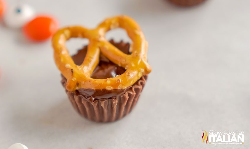 mini pretzel stuck on top of a mini reese's cup with melted chocolate