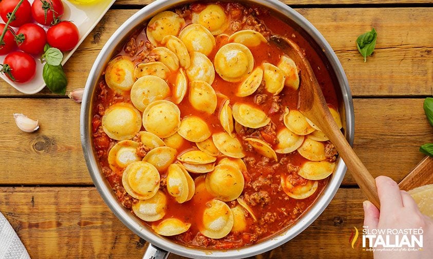 stirring mini ravioli into skillet with meat sauce