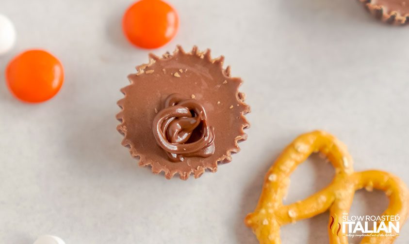 melted chocolate swirled on top of a mini reese's cup