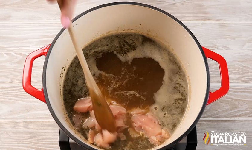 adding chicken breast to broth in a large pot