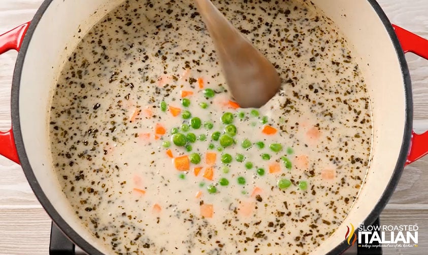 adding peas, carrots and cream to large pot