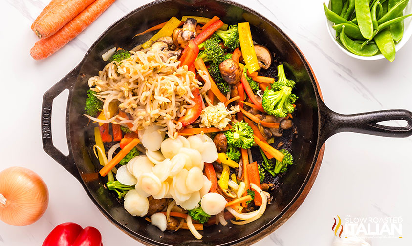 adding garlic, chestnuts, and bean sprouts to skillet