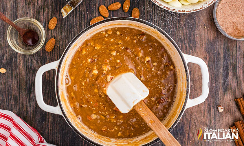 adding roasted almonds to saucepan with melted butter and sugar