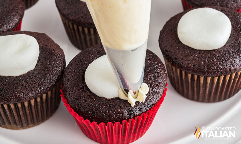 piping frosting onto a hot chocolate cupcake