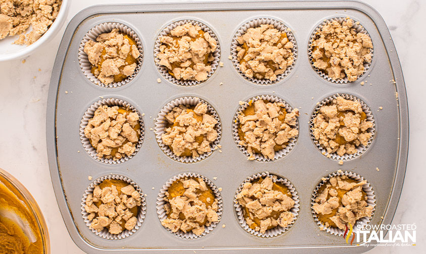 streusel topping adding to pumpkin muffins in muffin pan