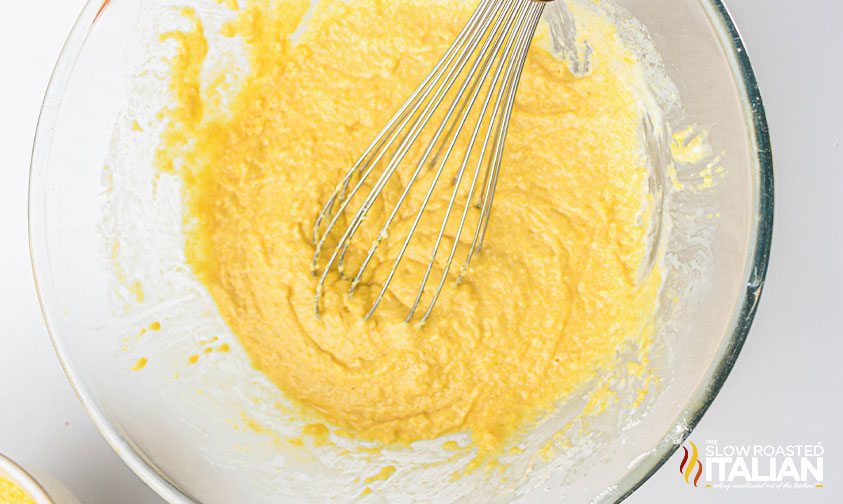 mixing air fryer cornbread batter in a bowl with a whisk