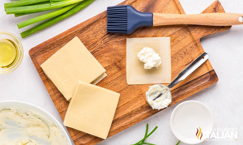 adding dollop of cream cheese mixture to wonton wrapper