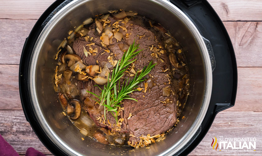 adding stock to instant pot with beef, mushrooms and onions