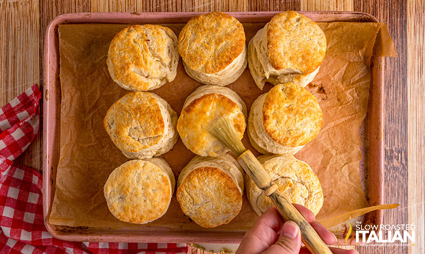 brushing baked cracker barrel biscuits with melted butter