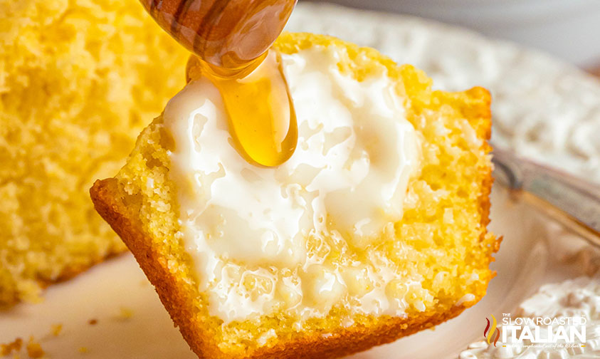 closeup of a sliced corn muffin with melted butter and drizzled honey