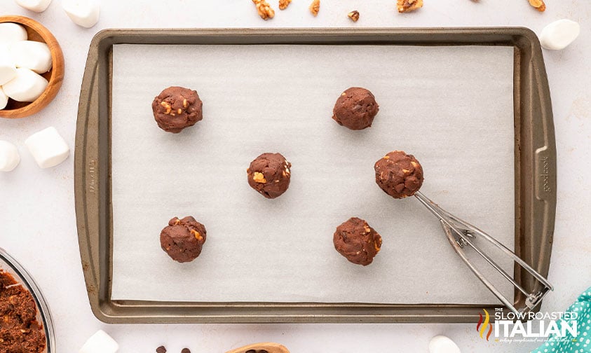 scoops of cookie dough on a parchment lined baking sheet