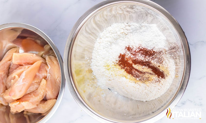 chicken tenderloins next to a bowl of flour and seasoning