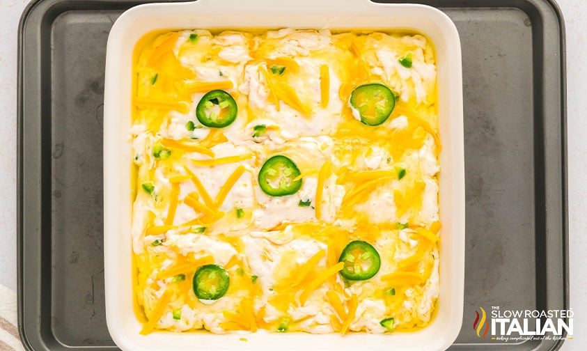 biscuit dough topped with cheddar and jalapenos in a baking dish