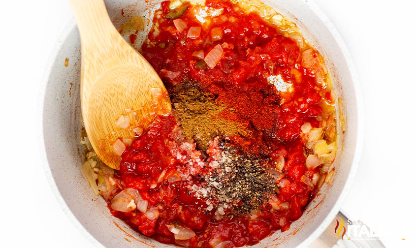 adding seasoning, tomatoes and cream to pot