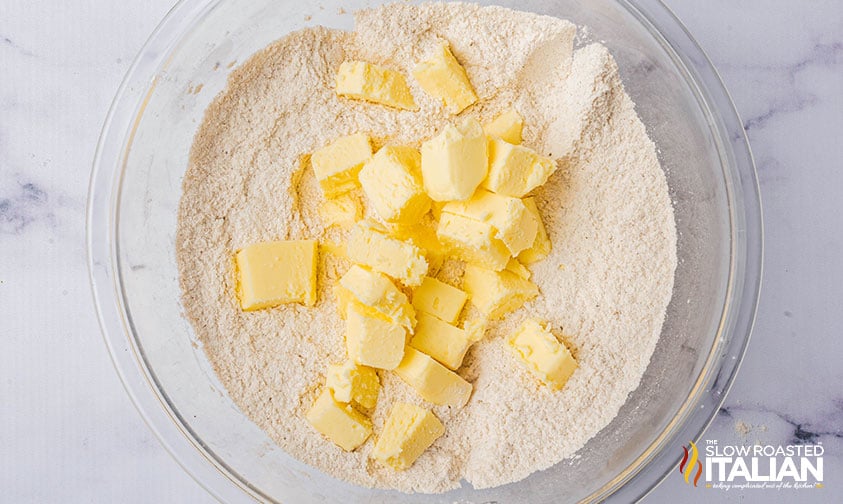 adding cold cubed butter to flour mixture in a large bowl