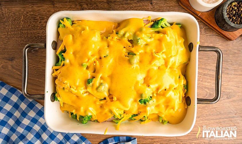 cheese sauce poured over chicken in baking dish