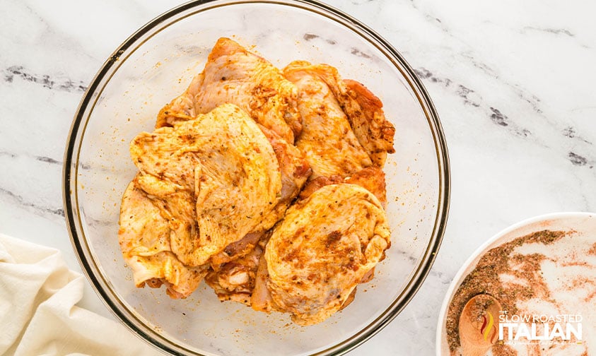 adding spices to chicken thighs