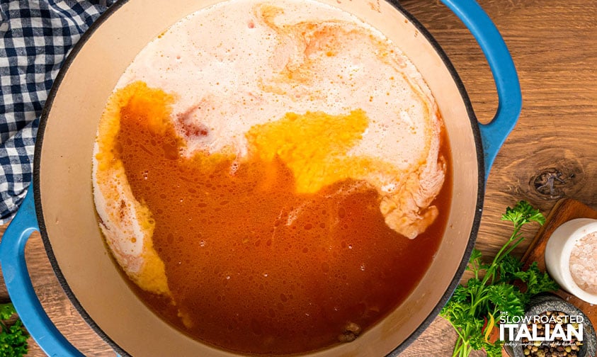 adding crushed tomatoes, chicken stock, and heavy cream to ground sausage in a large pot