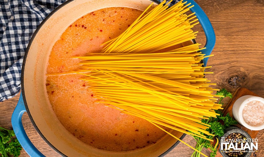 adding pasta to sauce in large pot