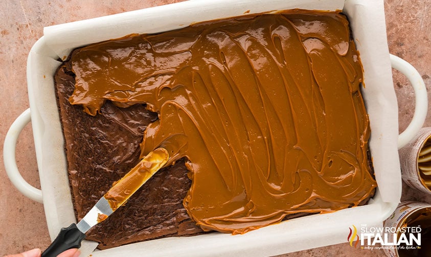 brownie layer covered in caramel layer in baking dish