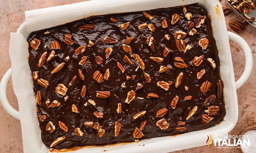 chocolate ganache on millionaire brownies with chopped pecans on top