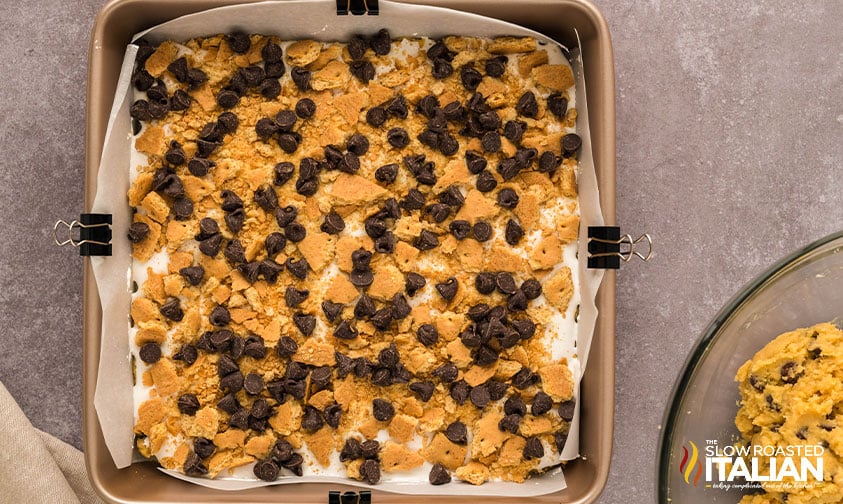 adding crushed graham crackers and chocolate chips to baking pan