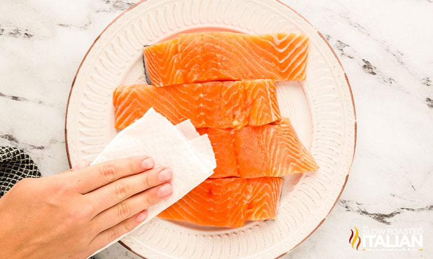 patting dry salmon with a paper towel