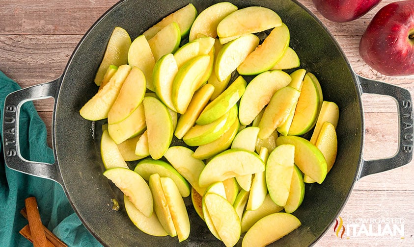 adding sliced apples to melted butter in a large skillet