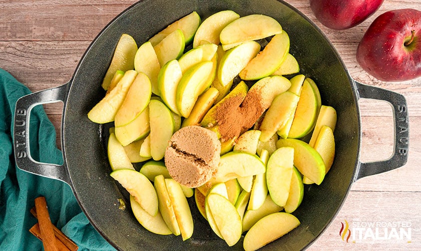 adding cinnamon and brown sugar to sliced apples in a large skillet