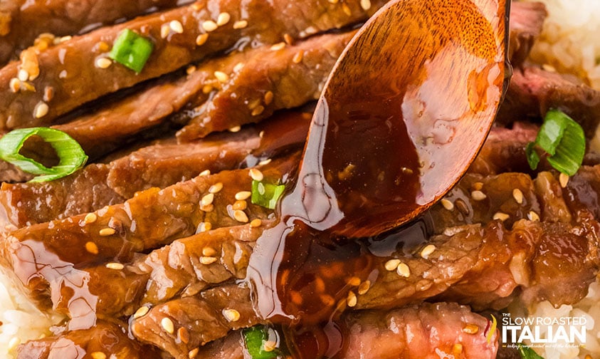 adding teriyaki sauce to sliced steak