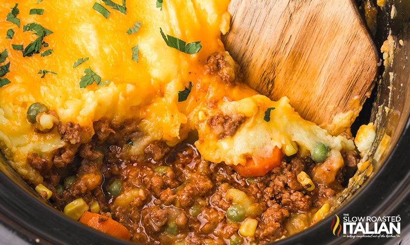 serving slow cooker cottage pie with a wooded serving spoon