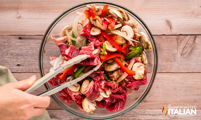 stirring in seasoning blend to steak and veggies in a large bowl