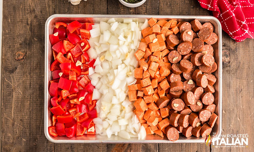 cut sausage, sweet potatoes, onion, and peppers on a baking sheet