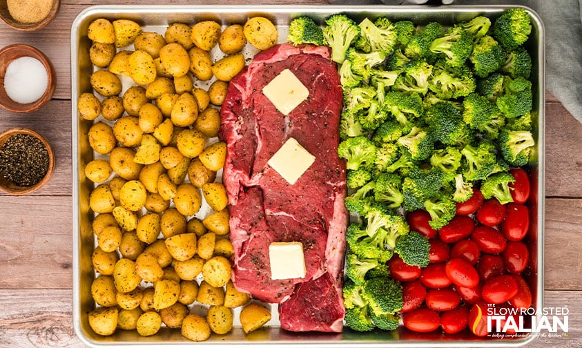 adding steak and veggies to sheet pan