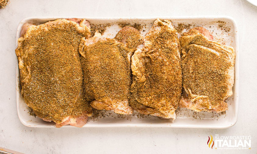 seasoned chicken thighs on a white tray